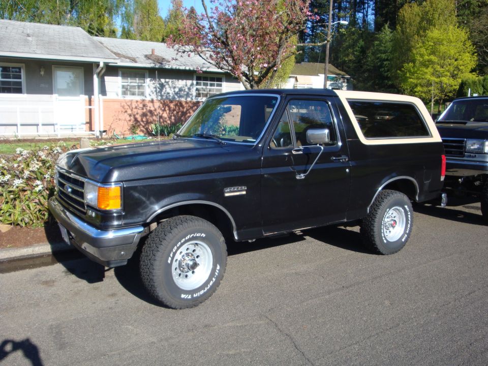 Black 1991 Ford Bronco with a tan top parked on a residential street