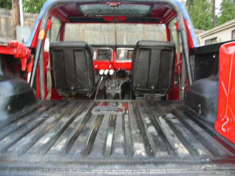 1979 Ford Bronco - The interior of a red SUV, likely a 1978 model, shows black seats, a roll cage, and a ribbed cargo bed.