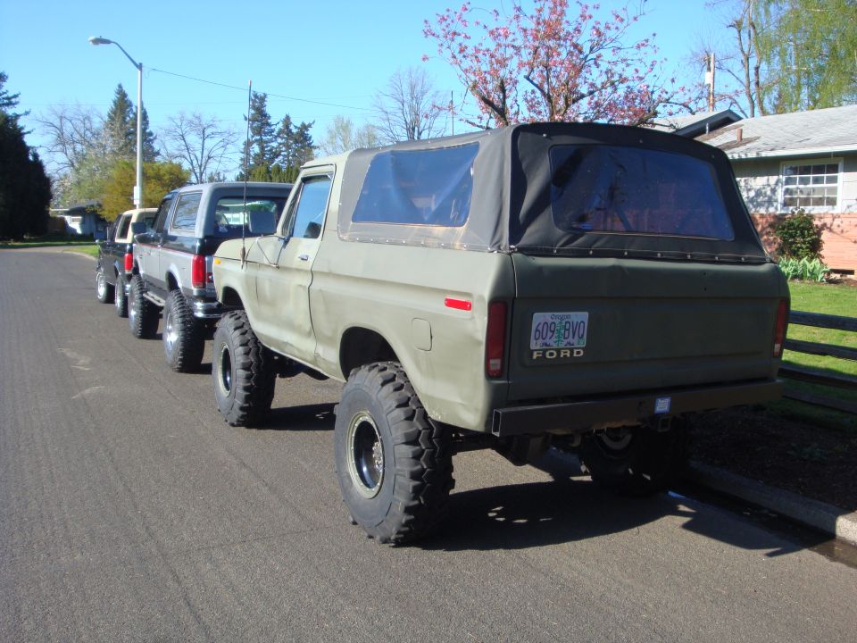 Olive green Ford Bronco with a black soft top, lifted suspension, and large tires. License plate reads 609 BVO
