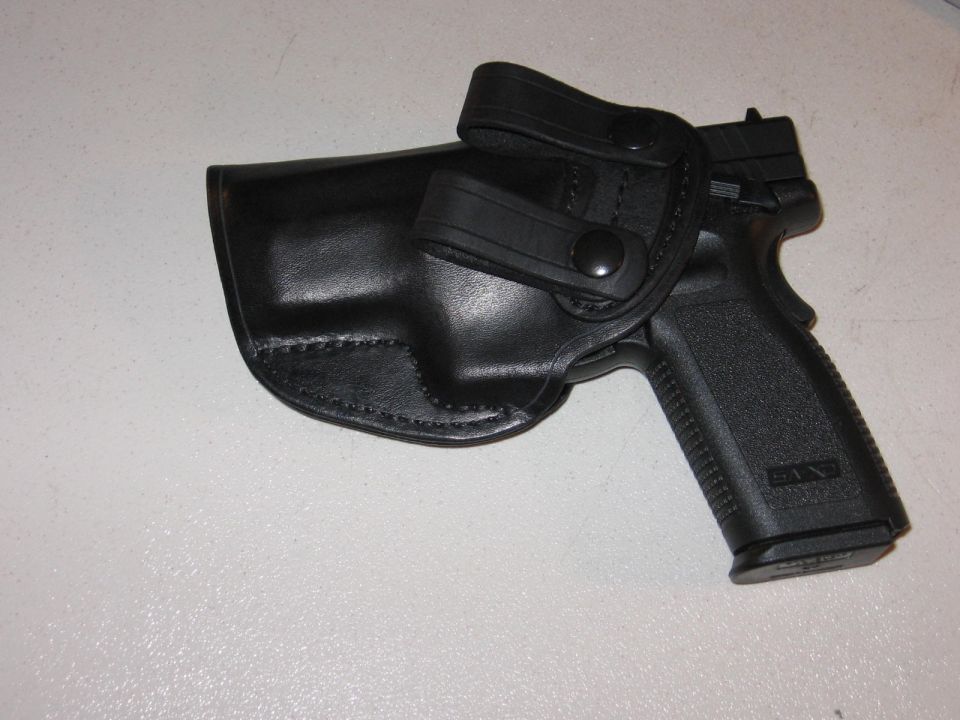 Black handgun in a black leather holster with snap closures