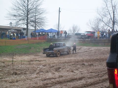 1979 Ford F-250 - A brown 1979 Ford F-250 navigates a muddy track, kicking up dust as spectators watch from the sidelines.