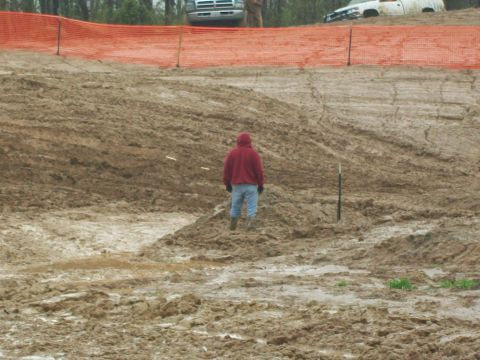 1979 Ford F-250 - Muddy construction site with trucks in the background and a person standing in the mud.