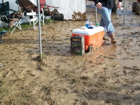 1979 Ford F-250 - A cooler sits in the mud next to a box with a monster truck graphic, with a person's legs visible in the background.