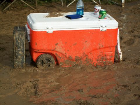 1979 Ford F-250 - An orange cooler with wheels is stuck in thick mud, with a bottle of water and two cans on top.