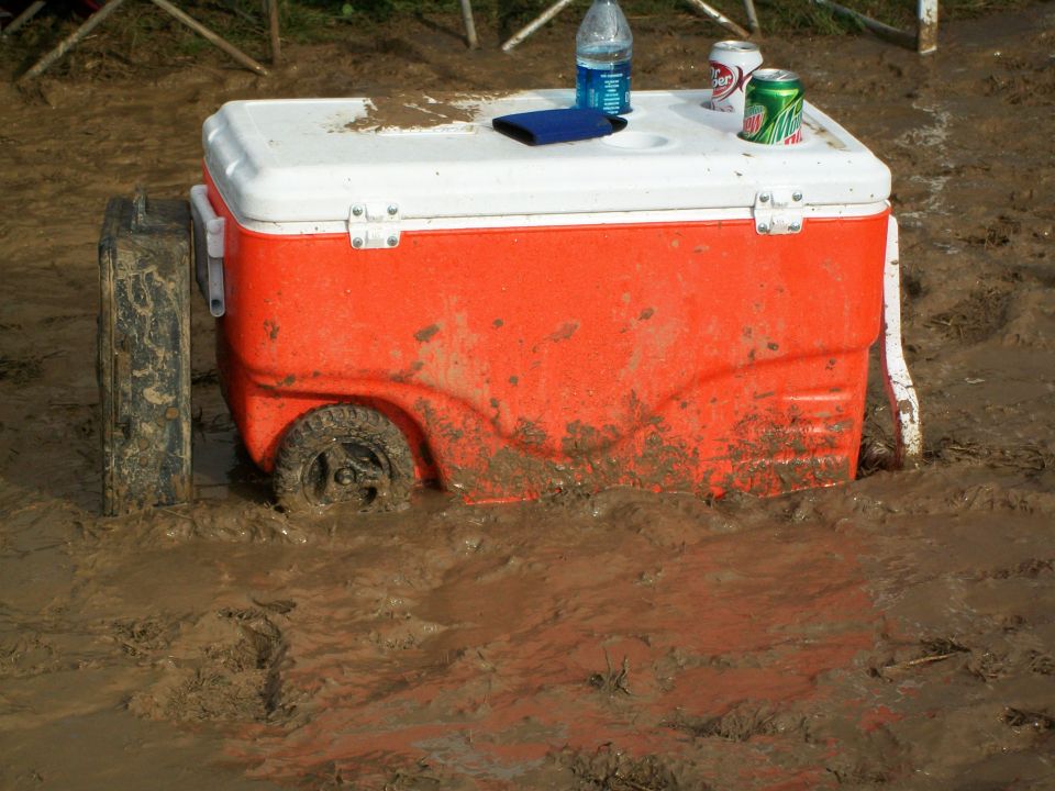 Orange cooler stuck in mud with wheels visible
