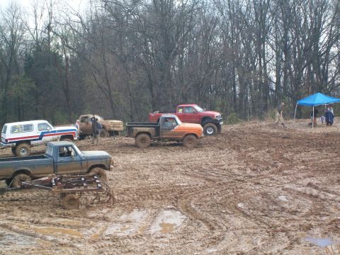 1979 Ford F-250 - Multiple trucks are stuck in a muddy field, with some appearing to have plows attached to the front.