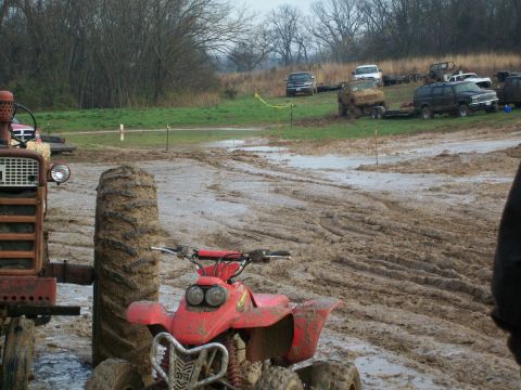 1979 Ford F-250 - Multiple vehicles are stuck in a muddy field, including a red ATV and a tractor.