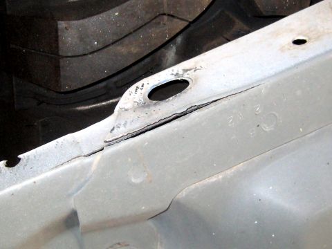 1996 Ford Bronco - A close-up view of a damaged metal component, possibly from a vehicle's chassis.