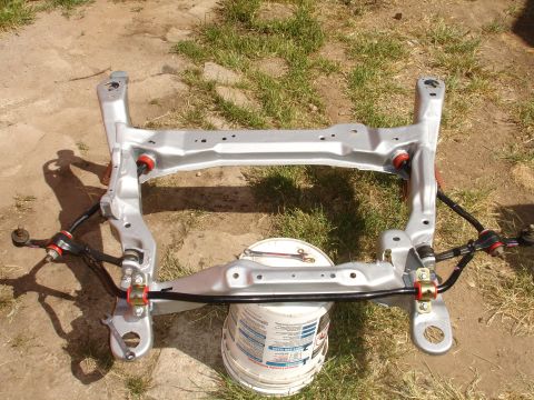 1995 Ford Taurus - Front subframe assembly, likely from a car, is shown resting on a bucket outdoors.