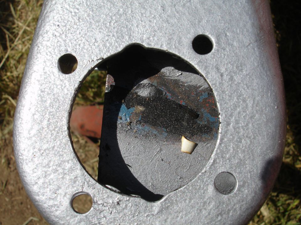 Close-up of silver-painted subframe bushing bore with torn rubber and blue paint traces