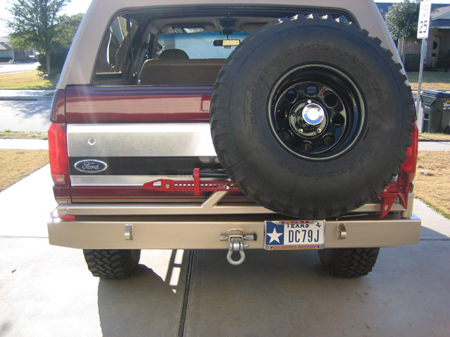 Rear of burgundy/tan Ford Bronco with swing-out spare tire carrier, custom bumper, and Texas plate DC79J