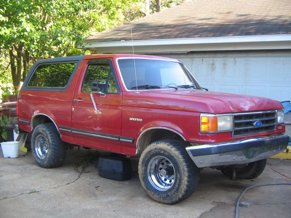Red 1991 Ford Bronco with a black top, parked in a driveway