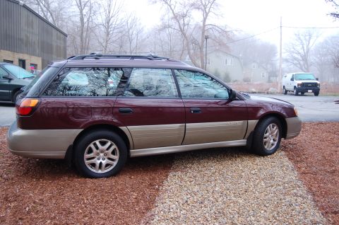 2001 Ford Crown Victoria - A two-tone Subaru Outback wagon is parked outside on a foggy day with a white van in the distance.