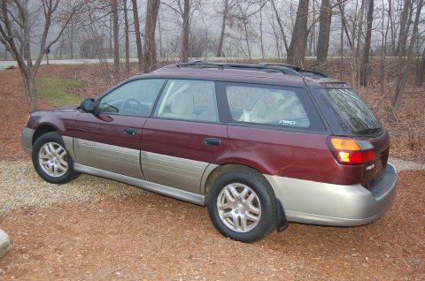 2001 Ford Crown Victoria - Maroon and tan Subaru Outback Wagon, likely a 2000 model, seen from the rear 3/4 angle.