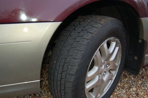 2001 Ford Crown Victoria - A close-up view of a vehicle's wheel well, showing the tire and part of the body panels.