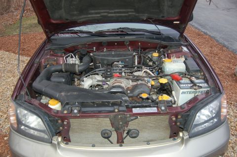 2001 Ford Crown Victoria - The engine bay of a maroon car is visible with the hood raised, revealing the engine and battery.