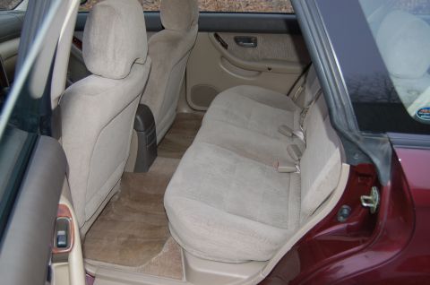 2001 Ford Crown Victoria - The interior of a maroon car, showing the rear seats, door panel, and floor mats.
