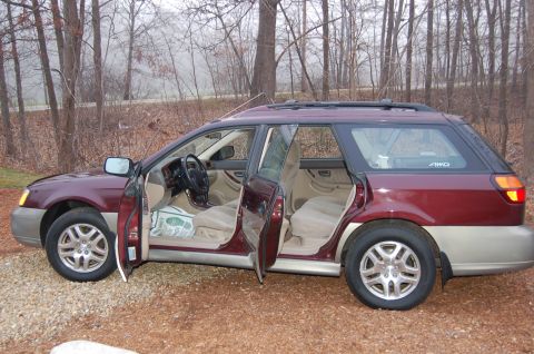 2001 Ford Crown Victoria - The interior of a maroon Subaru Outback wagon is visible with all doors open, parked outdoors on a gravel surface.