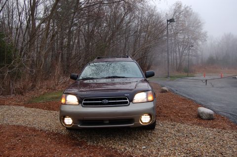 2001 Ford Crown Victoria - A Subaru Outback Wagon is parked outdoors on a foggy day, with its headlights and fog lights illuminated.