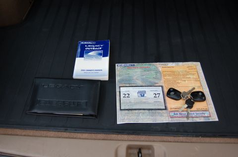 2001 Ford Crown Victoria - Owner's manual and window sticker for a Subaru Legacy Outback are laid out on a black mat.