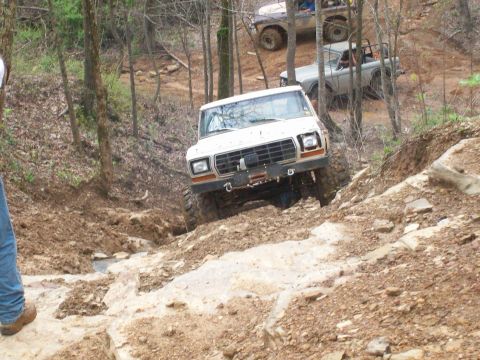 1978 Ford Bronco - Multiple off-road vehicles, including a 1978 Ford Bronco, tackle a challenging rocky incline.