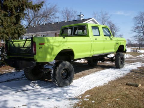 1974 Ford F-350 - This lifted pickup truck has a custom bed rack and is parked on a snowy driveway.