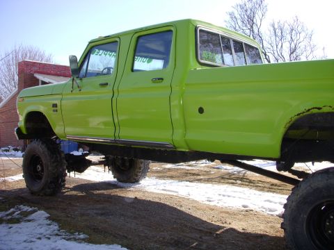 1974 Ford F-350 - This lifted lime green crew cab pickup truck has a side view, with text visible on the window.