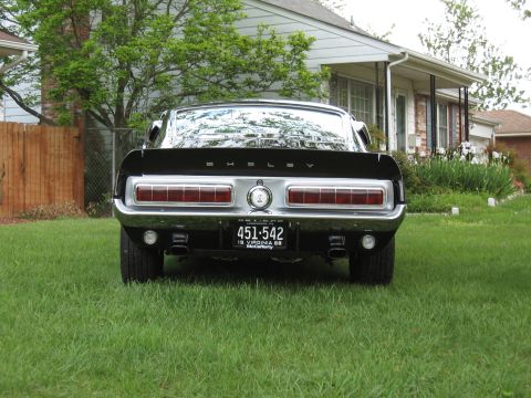 1968 Shelby GT500 - Rear view of a black 1968 Shelby GT500 parked on a grassy lawn in front of a house.