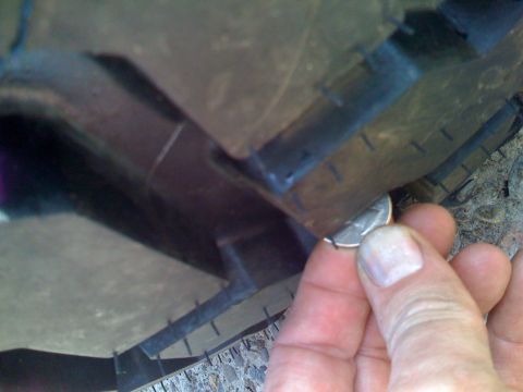 1985 Ford F-150 - A quarter is used to check the tread depth on a tire, indicating wear.