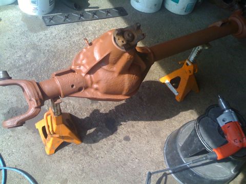 1985 Ford F-150 - A brown Dana 60 front axle assembly is supported by orange jack stands on a concrete surface.