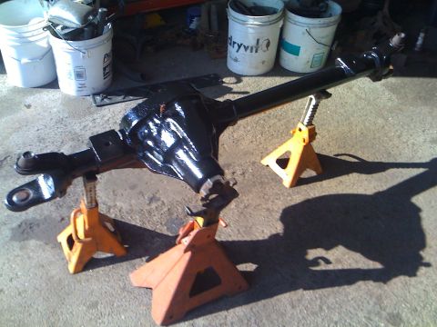 1985 Ford F-150 - A freshly painted front axle assembly is supported by jack stands in a workshop setting.