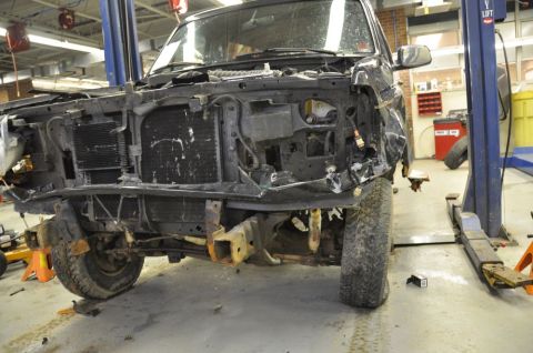 1996 Ford Bronco - This heavily damaged SUV is missing its front end components and is elevated on a lift for repairs.