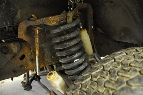 1996 Ford Bronco - Close-up view of the heavily rusted front suspension and tire of a vehicle.