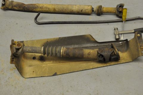 1996 Ford Bronco - Driveshaft and skid plate assembly, with a hammer and screwdriver nearby.