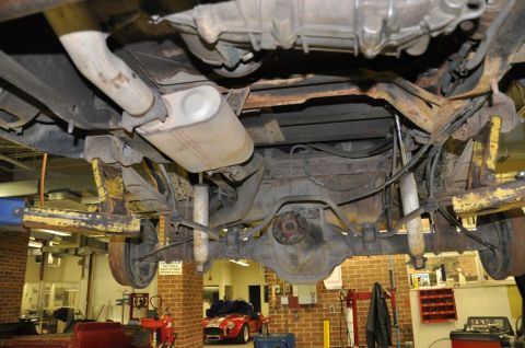 1996 Ford Bronco - Undercarriage of a vehicle, with a red sports car in the background.