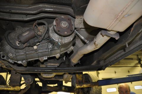 1996 Ford Bronco - The underside of a vehicle shows the transfer case and exhaust components, with a person visible in the background.