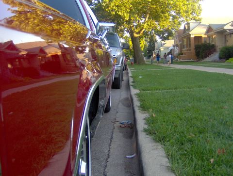 1990 Ford Crown Victoria LTD - Close-up of a red car's side, parked alongside a silver SUV on a suburban street.