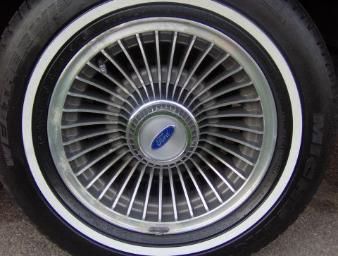 1990 Ford Crown Victoria LTD - Close-up of a Ford wheel with a whitewall tire and a blue Ford logo on the hubcap.