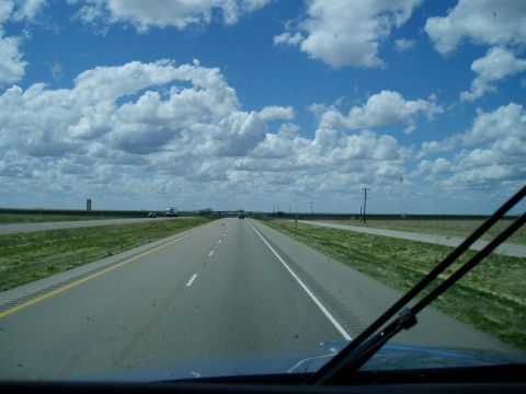 2009 Kenworth T800 - View from a vehicle driving on a highway under a cloudy blue sky.