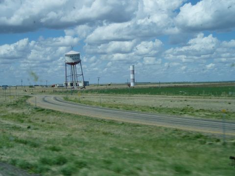 2009 Kenworth T800 - A water tower and a striped tower are visible in a rural landscape with a road curving through it.