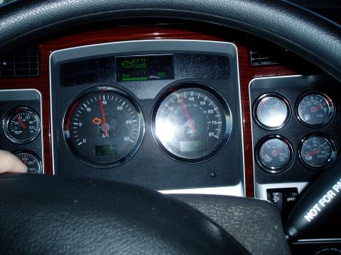 2009 Kenworth T800 - The interior of a truck shows a dashboard with multiple gauges and a digital display.