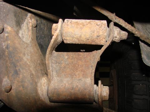 1979 Ford Bronco - Undercarriage view of a rusted leaf spring shackle mount, showing significant wear and tear.