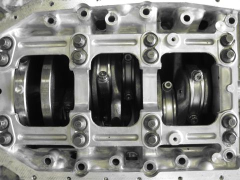 1994 Ford Probe - Close-up view of an engine's crankshaft and connecting rods, showing the bearing caps and bolts. The Supermotors.net logo is present in the…