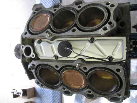 1994 Ford Probe - Close-up view of an engine block, showing pistons within the cylinders and a central metal plate with a wire attached.