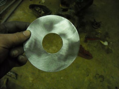 1979 Ford F-150 - A metal washer is held up for inspection, with a blurred background of what appears to be a workshop or garage.