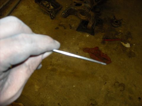 1979 Ford F-150 - Disassembled car parts and a hand holding a metal rod on a concrete floor.