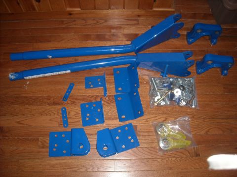 1979 Ford F-150 - Various blue metal suspension parts and hardware are arranged on a wooden floor.
