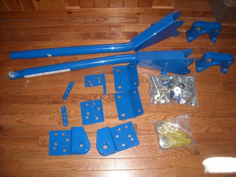 1979 Ford F-150 - A collection of blue suspension components and assorted hardware are displayed on a wood-planked surface.