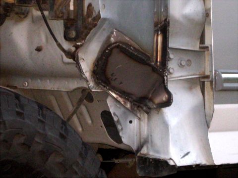 1996 Ford Bronco - Detail of a vehicle's frame showing recent welding work and a portion of a tire.
