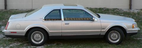 1990 Lincoln Mark VII - Side profile of a silver 1990 Lincoln Mark VII coupe, showing its distinctive body lines and sunroof.